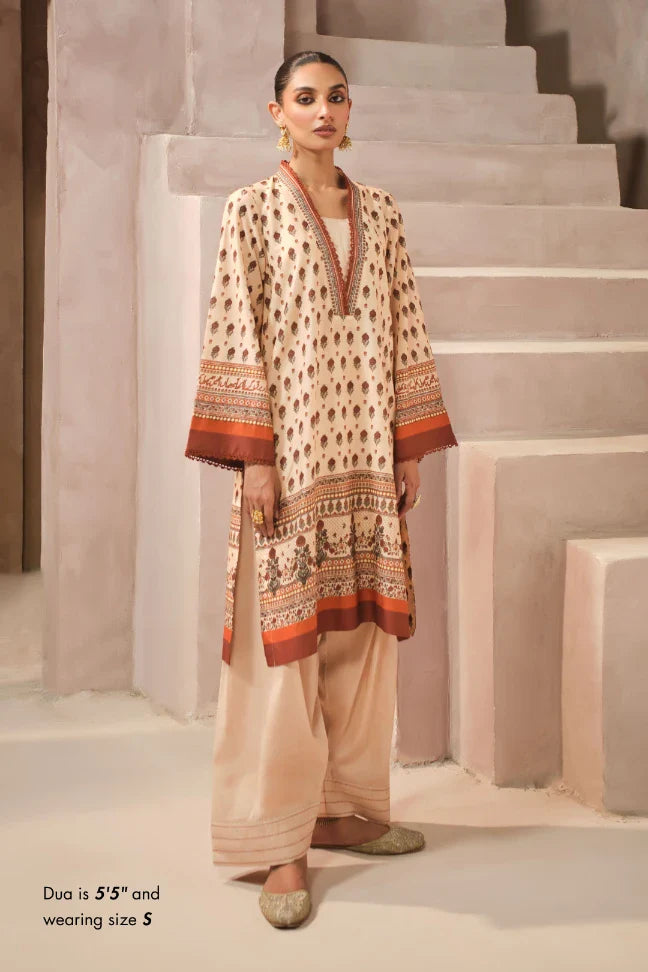 Woman wearing a patterned kurta with shalwar pants in a neutral setting