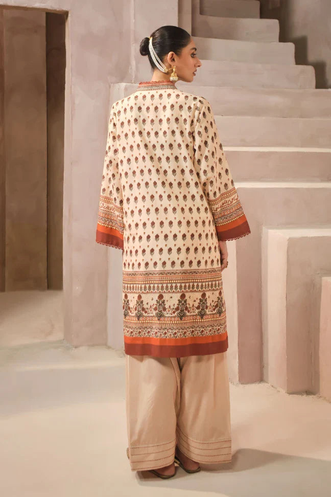Woman wearing a traditional outfit with a patterned top and beige pants, standing on a staircase.